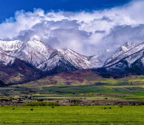 The Mountains Are Covered In Snow And Green Grass