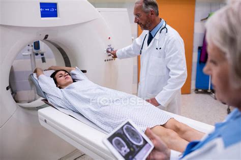 Doctor Looking At Brain Mri Scan On Digital Tablet And Patient Entering