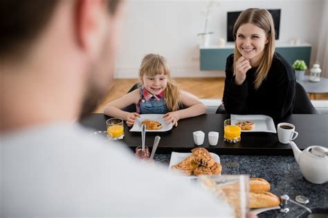 Hija Y Madre Mirando Padre Durante El Desayuno Foto Gratis