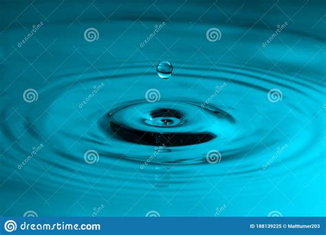 Perfect Water Drop Splashing Into Smooth Water Causing Ripples Stock
