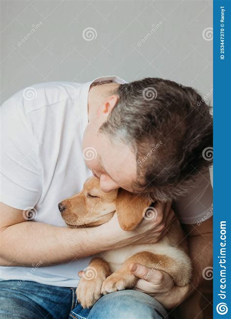 Young Man Hugging His Labrador Retriever Puppy The Concept Of