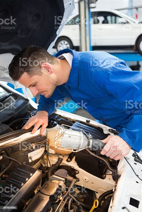 Mechanic Examining Under Hood Of Car With Torch Stock Photo Download