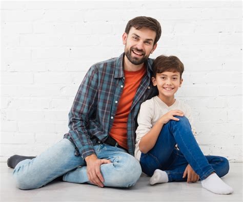 heureux père et fils assis sur le sol photo gratuite
