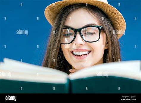 Portrait Of Beautiful Smiling Brunette Girl Wears Eyeglasses Reading The Book With Face