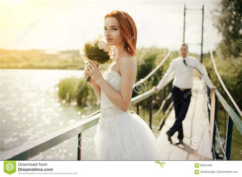 Bride And Groom Are Standing On The Bridge Stock Photo Image Of Hugg