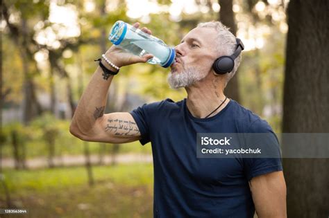 Sporty Man Drinking Water During Workout Outdoors Stock Photo