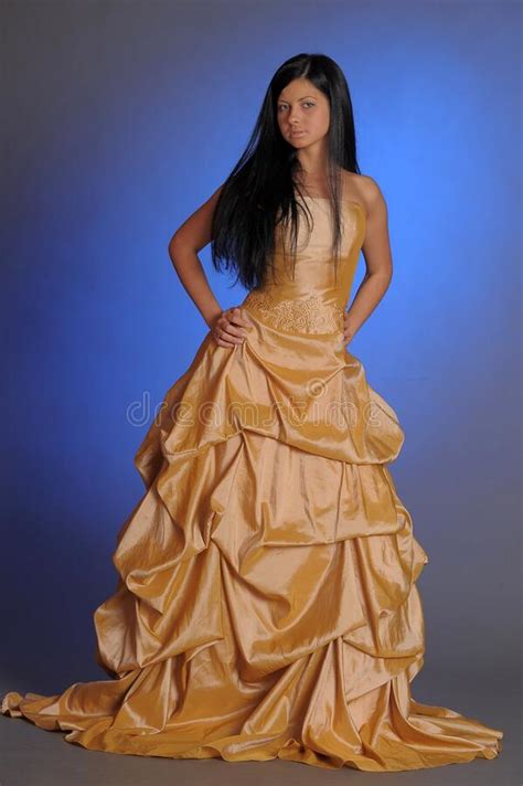 Brunette Girl In A Long Golden Dress In The Studio Stock Photo Image