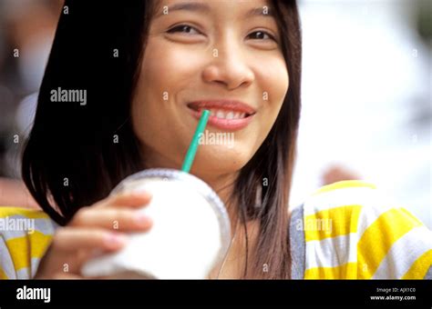 Young Thai Woman Sips Her Cold Drink In An Outdoor Cafe In Bangkok