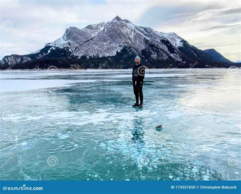 A Young Man Smiling Standing On The Middle Of A Frozen Lake With A