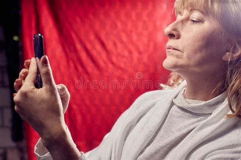 portrait of a middle aged woman with cell phone on a red background unprofessional female model