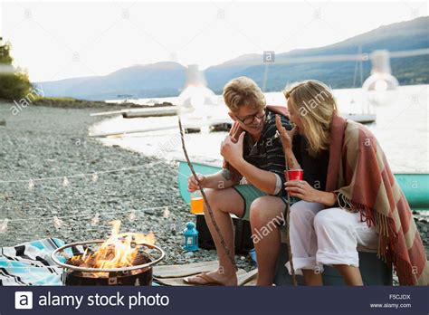Young Couple Roasting Marshmallows At Lakeside Campfire Stock Photo Alamy