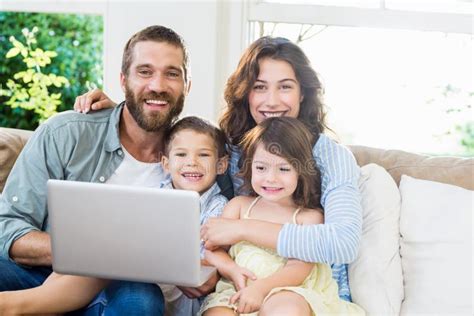 Portrait Of Parents And Kids Using Laptop In Living Room Stock Image