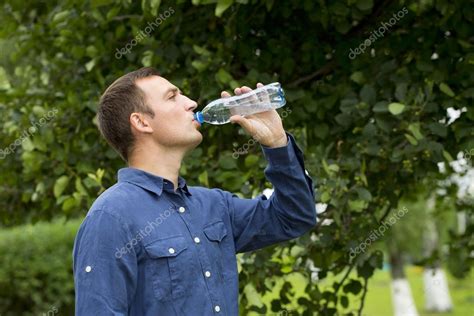 Handsome Man Drinking Water In A Park — Stock Photo © Arkusha 77543594