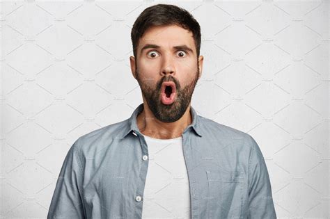 Stunned Shocked Young Bearded Male Stares At Camera With Widely Opened Mouth Being Surprised To