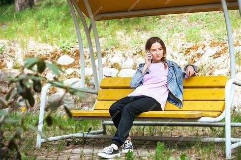 Расстроенная красивая девушка сидит на скамейке в парке на прогулке и Картинка - Расстроенная красивая девушка сидит на скамейке в парке на прогулке и