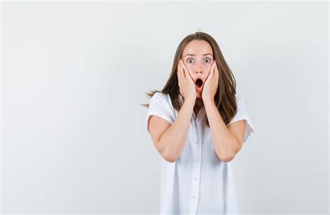 Jeune Femme Tenant Les Mains Sur Le Visage En Chemisier Blanc Et à La