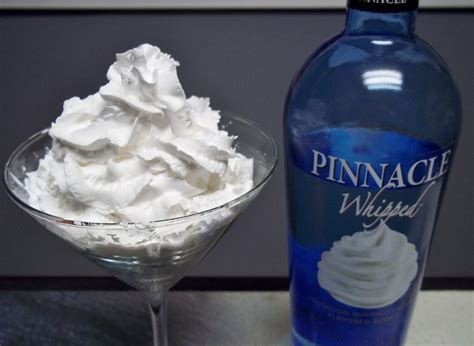 a glass with whipped cream in it next to a bottle of pinnacche wine