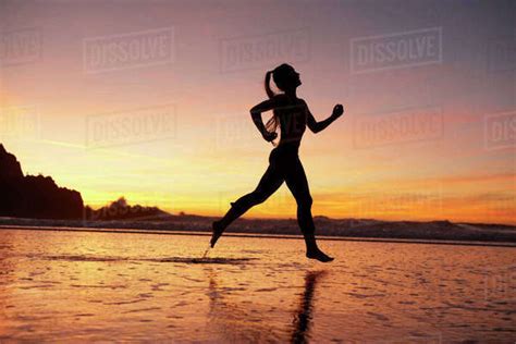 Silhouette Of Woman Running On Beach At Sunset Stock Photo Dissolve