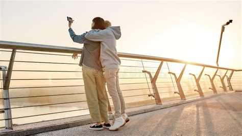 Creating Moments Full Length Shot Of Lesbian Couple Standing On The Bridge And Hugging Each