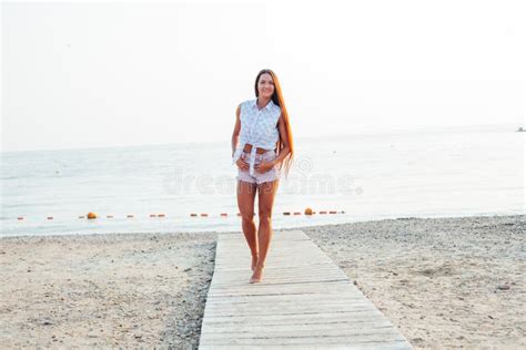 Tanned Woman With Long Hair Walks On Beach By The Sea Stock Image