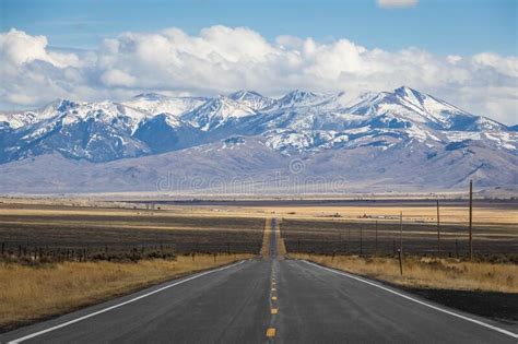 A Long Straight Road Heading Into The Distant Mountains Stock Photo