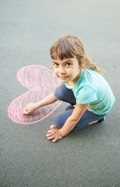 Premium Photo The Child Paints Chalk On The Asphalt Heart Selective