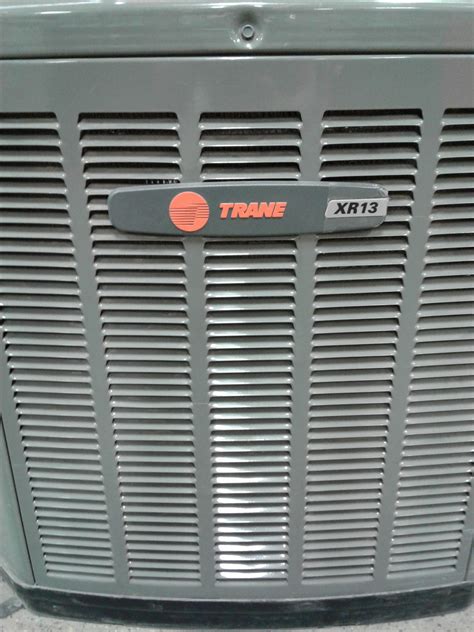 An Air Conditioner Sitting On The Ground Next To A Wall With A Sticker