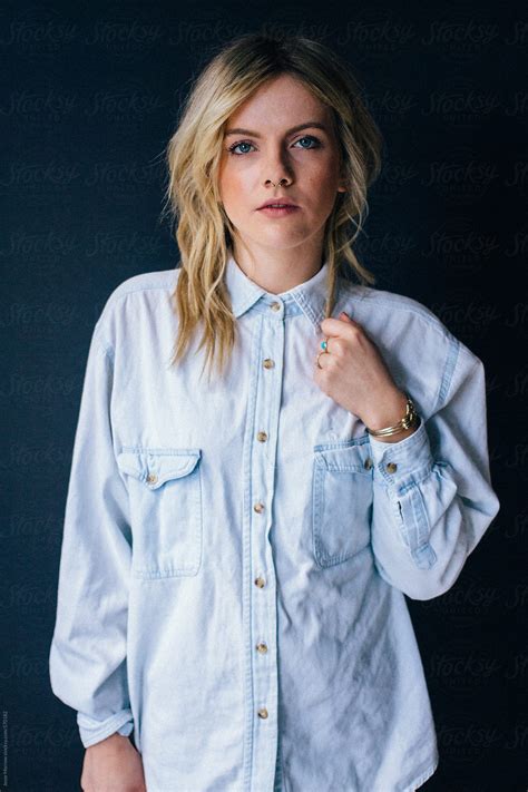 Young Attractive Blonde Female In Blue Denim Shirt On Dark Background