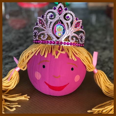 A Pink Pumpkin With A Crown On Its Head Sitting On Top Of A Table