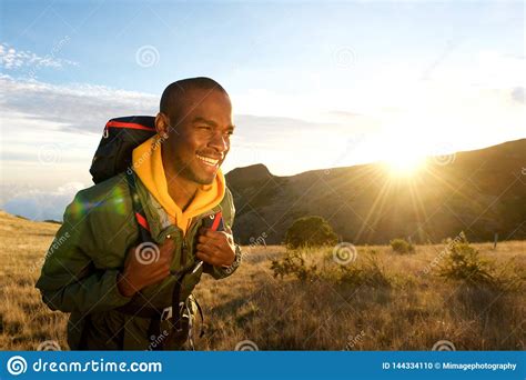 Young Black Man Walking With Backpack In Mountains With Sunrise In
