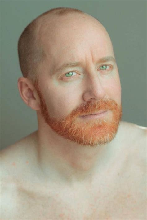 A Man With A Red Beard And No Shirt Looking At The Camera While Posing