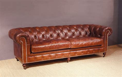 A Brown Leather Couch Sitting On Top Of A Wooden Floor Next To A Gray Wall