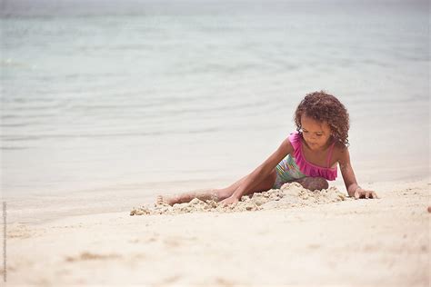 Young Girl Lying Down And Playing In The Sand By Anya Brewley