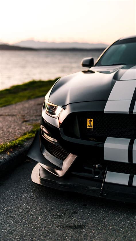 The Front End Of A Black Sports Car With White Stripes On It S Hood