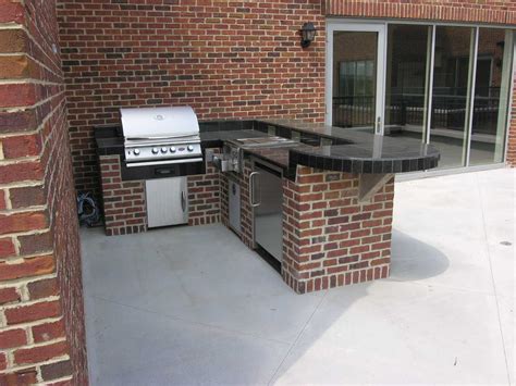 L Shaped Brick Outdoor Kitchen With A Grill Refrigerator And Burners