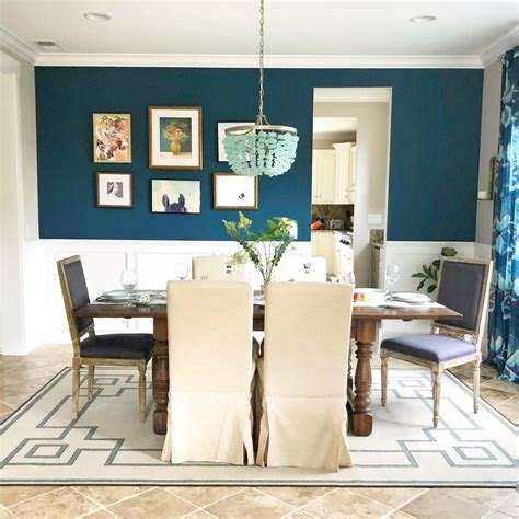 A Dining Room With Blue Walls And Pictures Hanging On The Wall Above