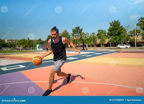 A Male Basketball Player Runs On A Basketball Court With A Ball Stock