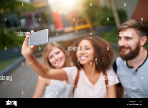 Outdoor Shot Of Young Woman Taking Self Portrait On Mobile Phone With