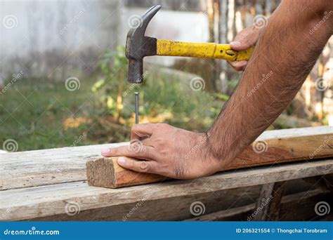 The Carpenter Was Hammering The Nails Into The Wood With An Iron Hammer