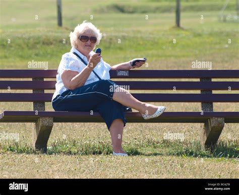 Vieille Femme Tait Assise Sur Le Banc De Parc Texting Photo Stock Alamy
