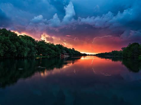 Sunset Peaceful River Coast With Green Trees Forest Red Sky Lightning