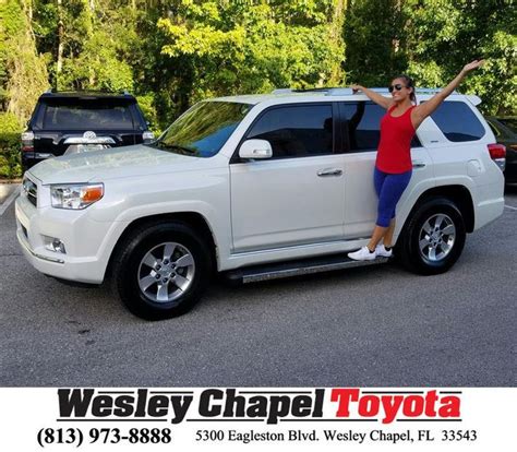 A Woman Standing In Front Of A White Toyota Suv With Her Arms Up And