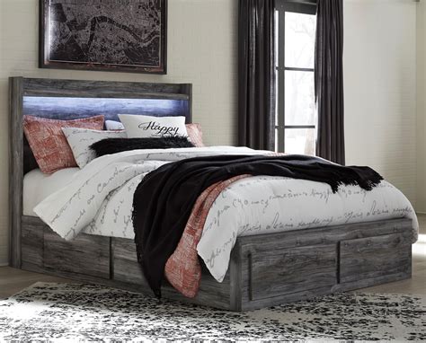 Featuring an attractive rugged brown finish that flows smoothly over replicated oak grain, this q. Ashley Signature Design Baystorm Queen Storage Bed with 6 ...