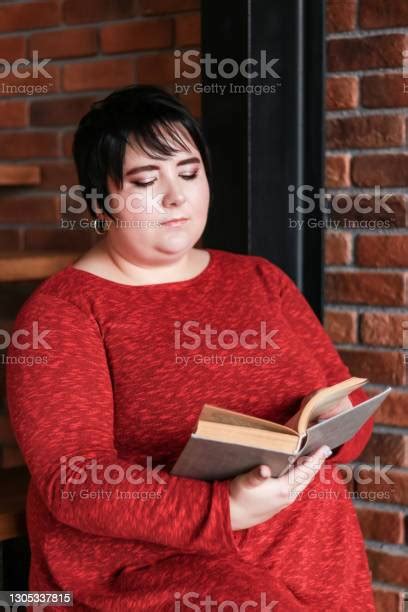 Plump Brunette With Short Hair In A Red Dress Reading A Book On A Red