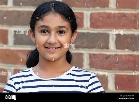 Portrait Of A Smiling Little Girl Against A Brick Background Stock