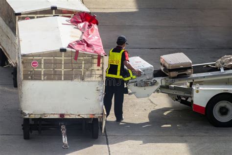 Asian Man Loader Lifting Up The Luggage To Conveyor Belt Of The Trailer