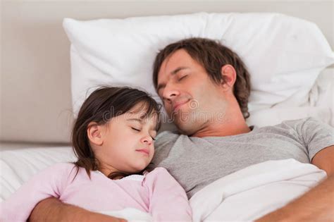 Hija Que Duerme Al Lado De Padre En Cama En Casa Imagen De