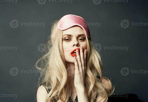 Blonde Woman Smeared Makeup On Her Face On A Gray Background And A Pink Sleep Mask On Her Head