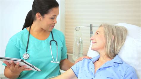 Hospital Consultant Nurse Giving Medical Care To Senior Retired Female