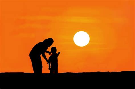 Silueta De Madre E Hijo De Pie En La Montaña Viendo La Puesta De Sol